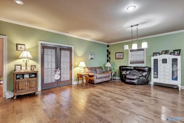 living area with baseboards, visible vents, ornamental molding, and wood finished floors