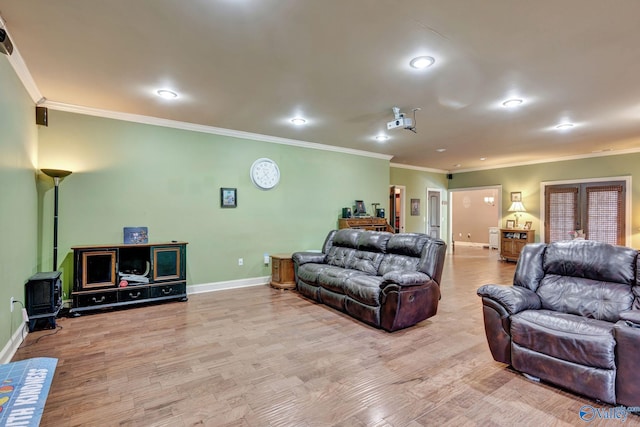 living room featuring a wood stove, crown molding, baseboards, and wood finished floors