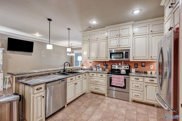 kitchen featuring cream cabinetry, stainless steel appliances, visible vents, a sink, and a peninsula