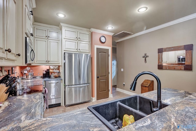 kitchen with stainless steel appliances, dark countertops, crown molding, and a sink