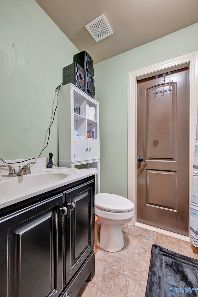 bathroom featuring toilet, vanity, and visible vents