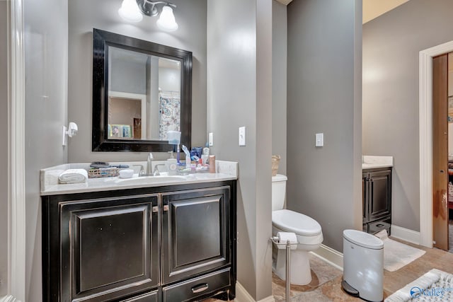 full bathroom featuring toilet, baseboards, and vanity