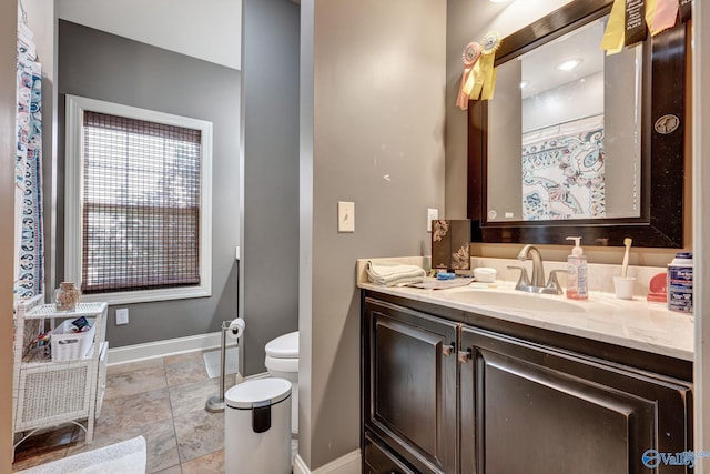 bathroom with toilet, baseboards, and vanity