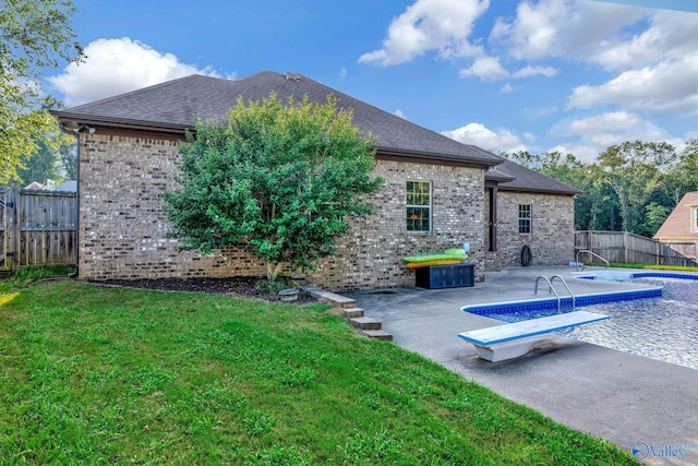 back of property featuring a lawn, a fenced backyard, roof with shingles, a patio area, and brick siding