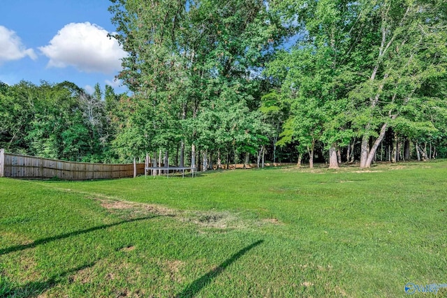 view of yard featuring a trampoline and fence