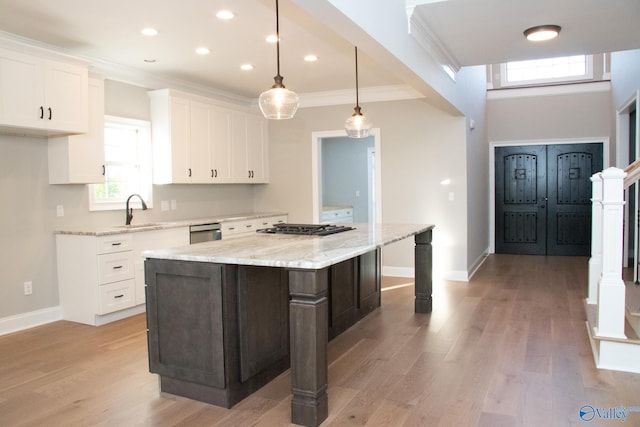 kitchen featuring white cabinetry, sink, light stone counters, a kitchen island, and light hardwood / wood-style flooring