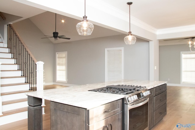 kitchen featuring light hardwood / wood-style flooring, pendant lighting, a kitchen island, ceiling fan, and stainless steel range with gas stovetop