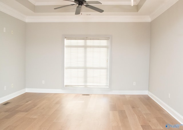 unfurnished room with light hardwood / wood-style floors, ornamental molding, ceiling fan, and a raised ceiling