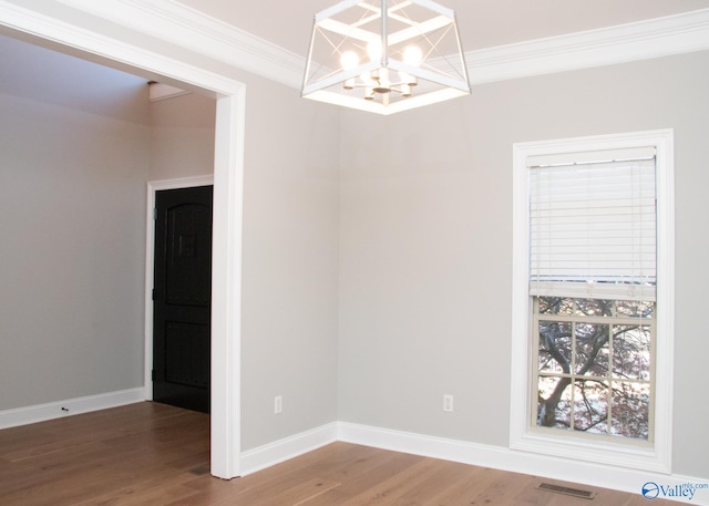 spare room with a notable chandelier, hardwood / wood-style floors, and ornamental molding