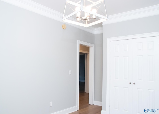 unfurnished bedroom with an inviting chandelier, hardwood / wood-style flooring, ornamental molding, and a closet