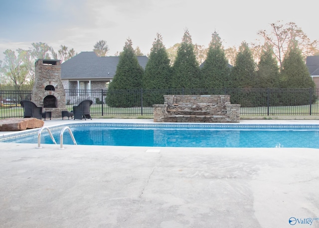 view of swimming pool with a fireplace and a patio