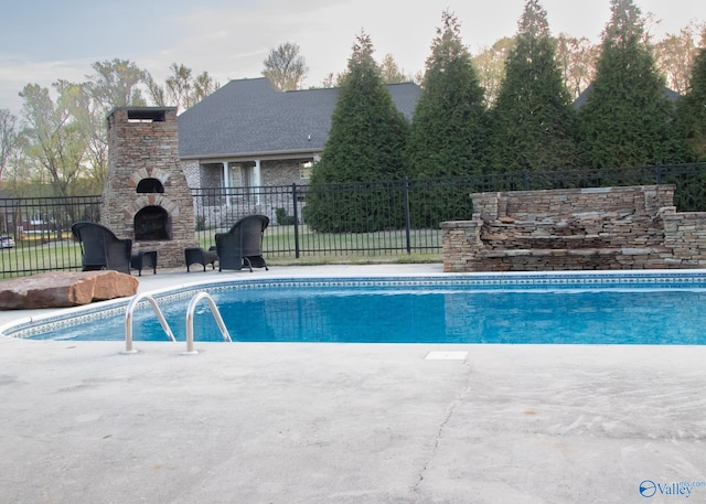 view of pool featuring an outdoor stone fireplace