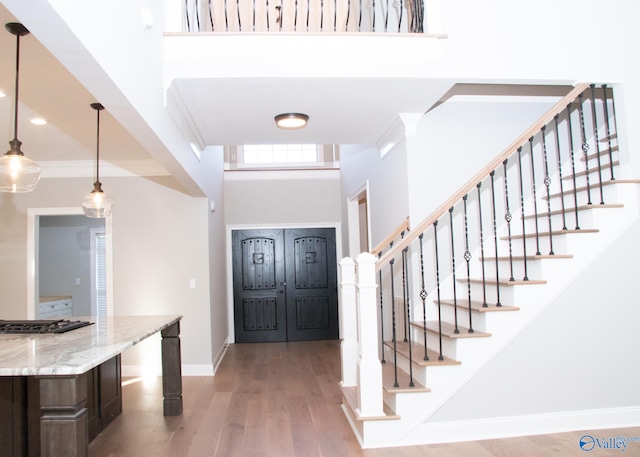 entrance foyer featuring crown molding, light wood-type flooring, and a towering ceiling