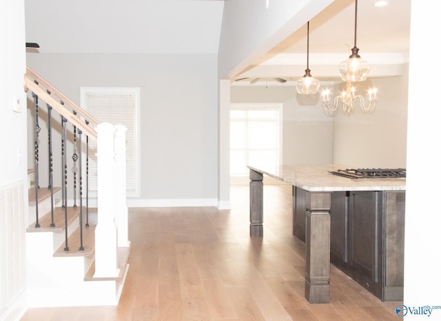 kitchen featuring dark brown cabinetry, light stone counters, hanging light fixtures, light wood-type flooring, and a notable chandelier