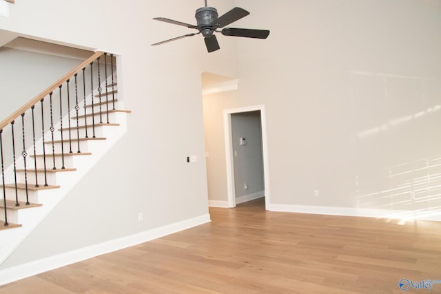 interior space with ceiling fan, light hardwood / wood-style floors, and a towering ceiling