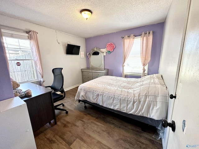 bedroom with multiple windows, wood finished floors, baseboards, and a textured ceiling