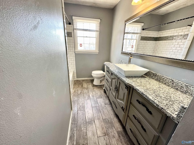 bathroom featuring baseboards, walk in shower, wood finish floors, toilet, and vanity