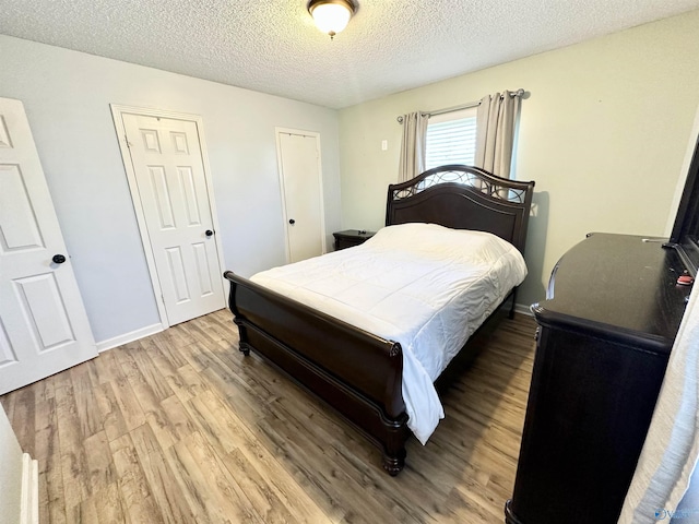 bedroom featuring light wood-style flooring, a textured ceiling, and baseboards