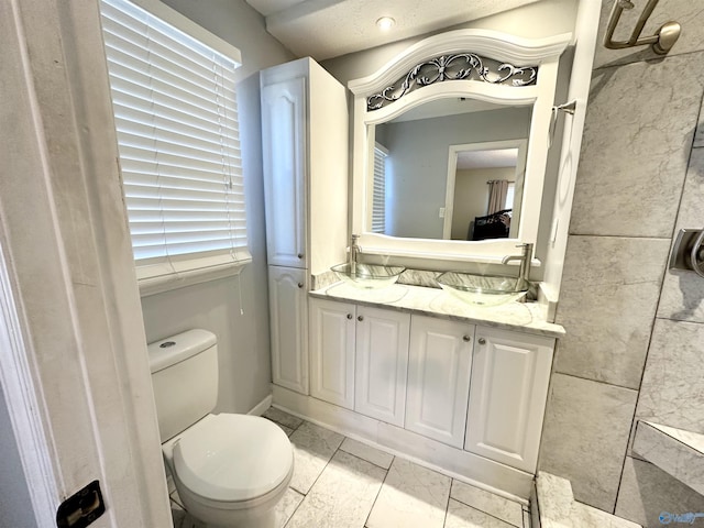 full bath with double vanity, toilet, and a sink