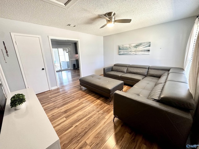 living area with visible vents, light wood-style floors, ceiling fan, and a textured ceiling