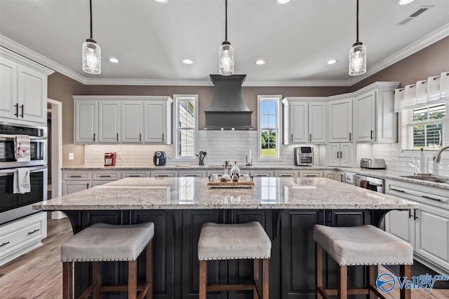 kitchen with a sink, white cabinetry, backsplash, and custom exhaust hood