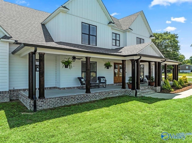 rear view of house featuring a lawn, roof with shingles, a ceiling fan, board and batten siding, and a porch