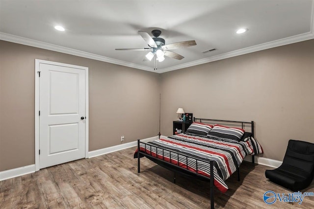 bedroom with baseboards, ornamental molding, wood finished floors, and visible vents