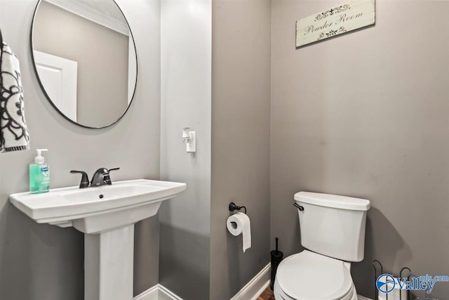 bathroom featuring toilet, baseboards, and a sink