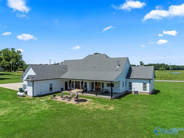 back of property featuring roof with shingles, a patio, and a yard