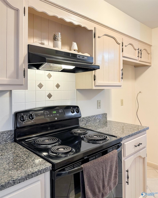 kitchen with tasteful backsplash, black electric range oven, light tile patterned floors, and dark stone counters