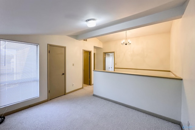 carpeted spare room with a chandelier and vaulted ceiling with beams