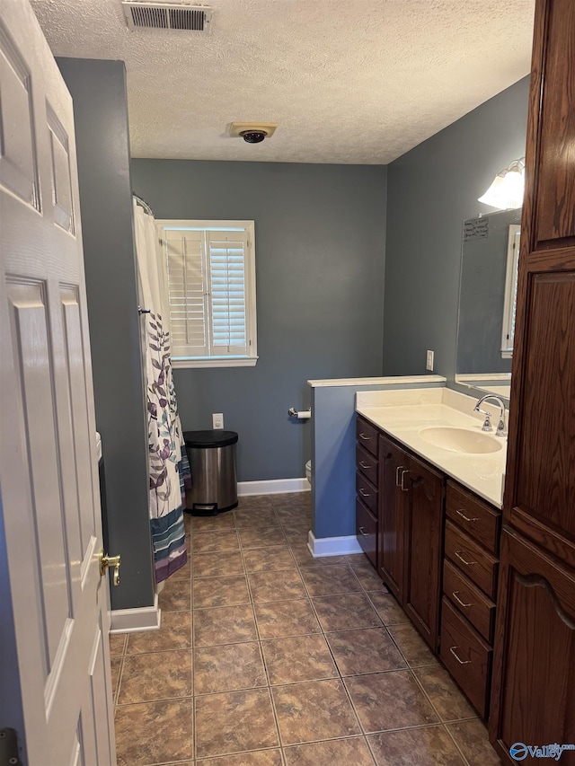 bathroom featuring visible vents, a textured ceiling, vanity, and toilet