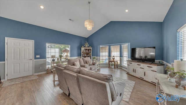 living area with lofted ceiling, light wood-style floors, visible vents, and baseboards