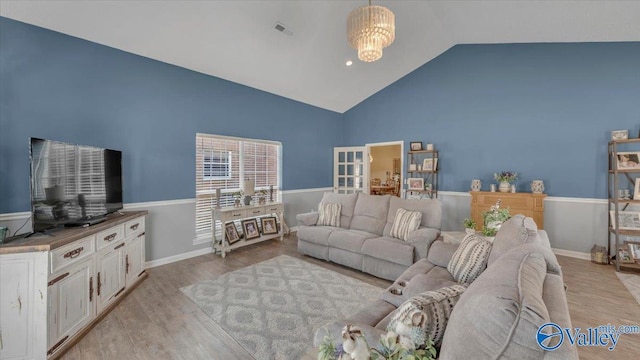 living area with baseboards, visible vents, light wood finished floors, and high vaulted ceiling