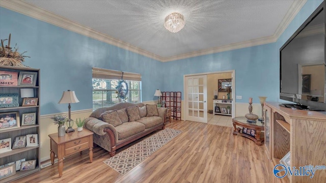 living area featuring french doors, a textured ceiling, wood finished floors, and ornamental molding