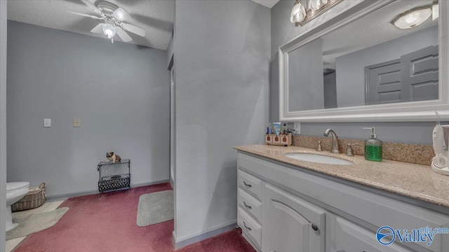bathroom with vanity, toilet, baseboards, and ceiling fan