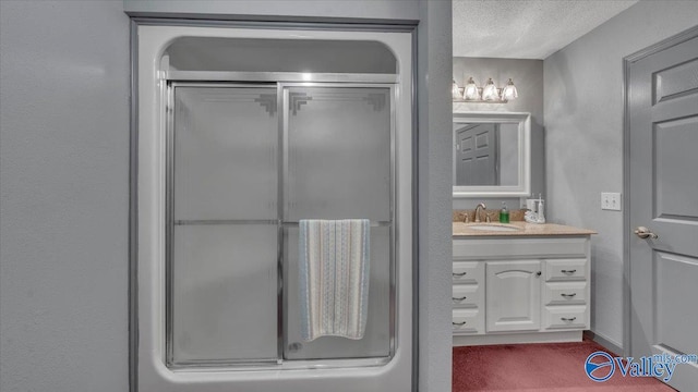full bath with a textured ceiling, vanity, a textured wall, and a shower with shower door