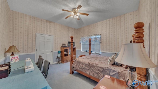 bedroom featuring wallpapered walls, carpet flooring, a ceiling fan, and a textured ceiling