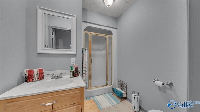 full bath with wood finished floors, a textured ceiling, a stall shower, and vanity