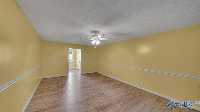 spare room with a textured ceiling, a ceiling fan, baseboards, and wood finished floors