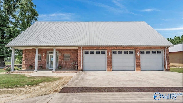 view of front facade with brick siding, driveway, metal roof, and a garage