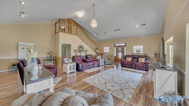 living room with wood finished floors, stairs, and ornamental molding