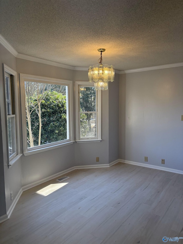 unfurnished room with hardwood / wood-style flooring, ornamental molding, a chandelier, and a textured ceiling