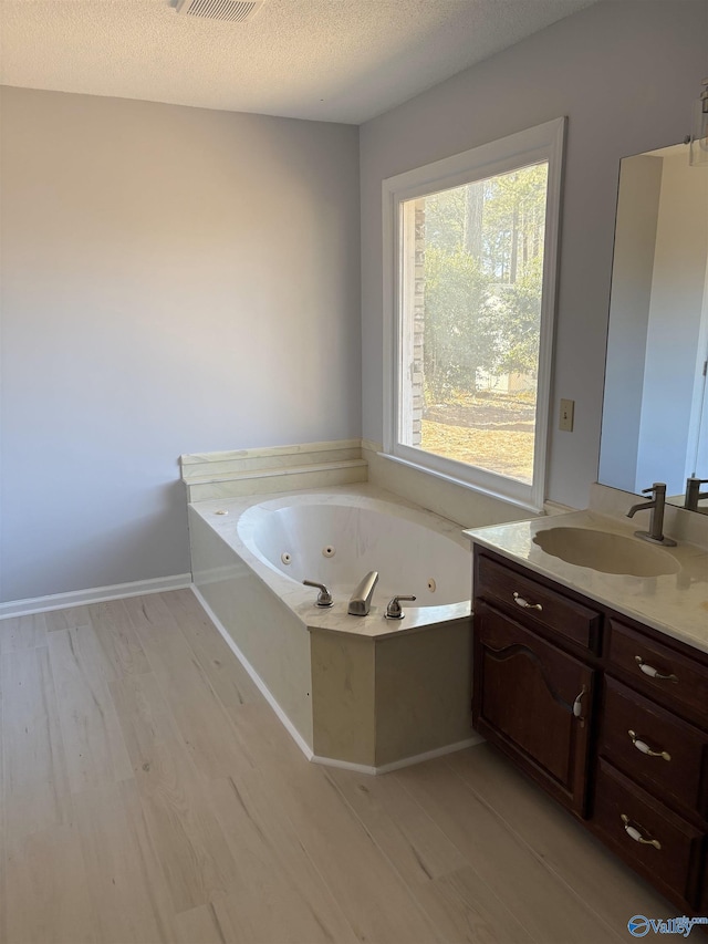 bathroom with vanity, hardwood / wood-style flooring, a bathing tub, and a textured ceiling