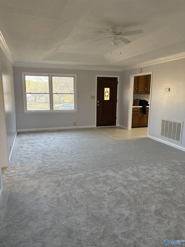 unfurnished living room featuring light carpet, a tray ceiling, ornamental molding, and ceiling fan