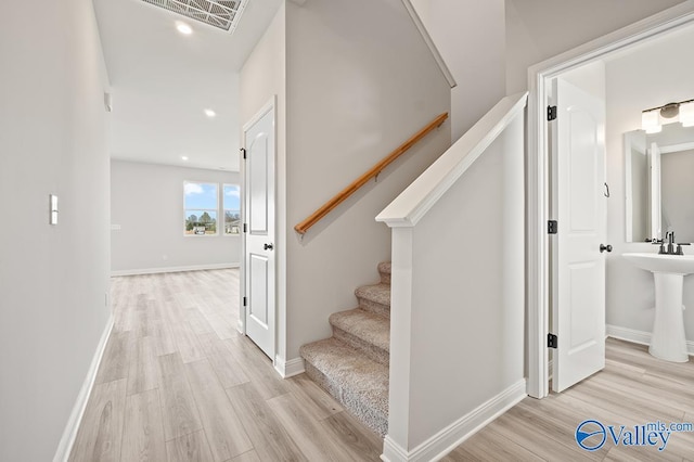 stairway with hardwood / wood-style floors and sink