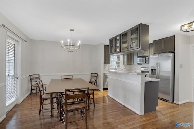 dining room featuring baseboards, light wood-style flooring, and a notable chandelier