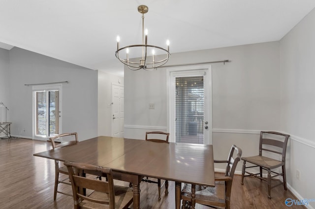 dining space with lofted ceiling, baseboards, wood finished floors, and a chandelier