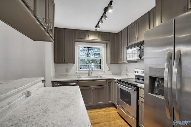 kitchen with light wood-style floors, dark brown cabinets, stainless steel appliances, and a sink