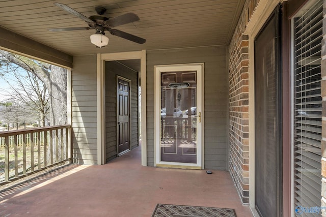 view of exterior entry with ceiling fan and brick siding